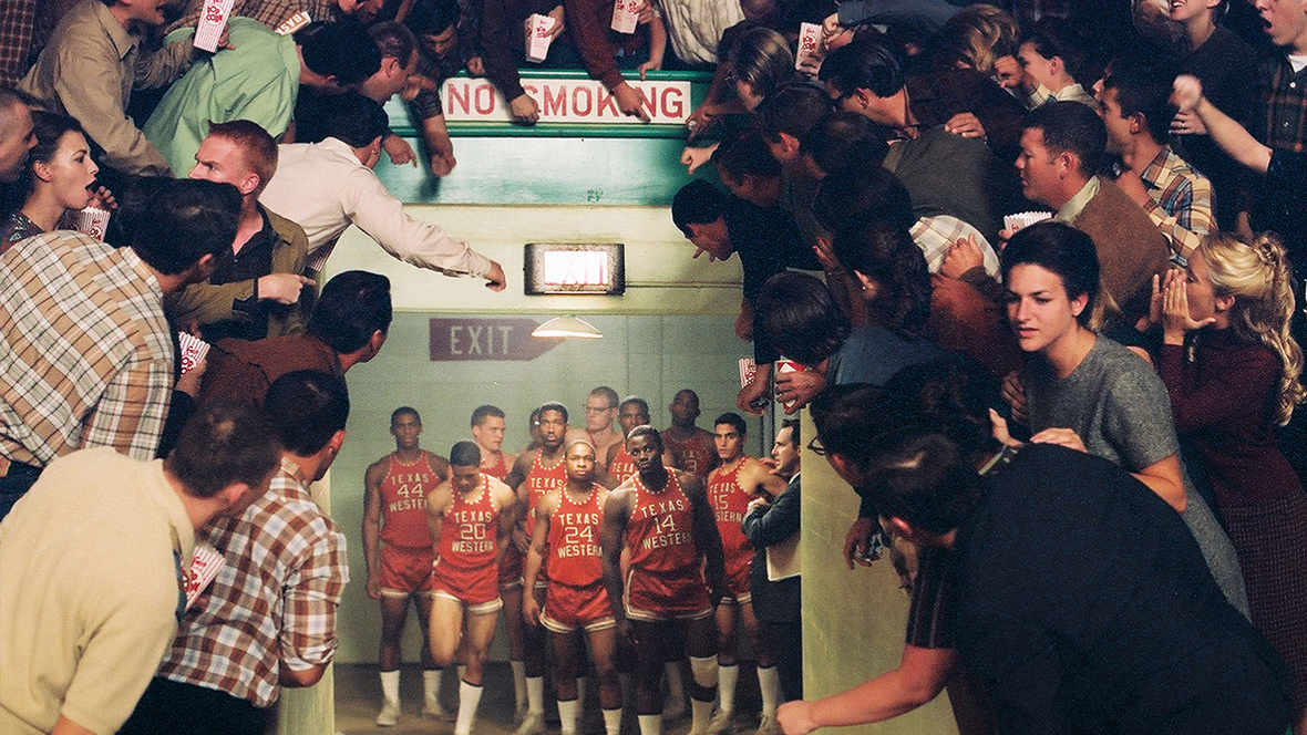 A still from the film Glory Road; featuring the Texas Western Miners basketball team as they enter the gym from the locker room tunnel for the start of the game. An angry crowd is shouting at them from around the tunnel.