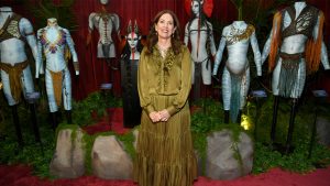 An image of costume designer Deborah L. Scott surrounded by costumes from Avatar: Fire and Ash