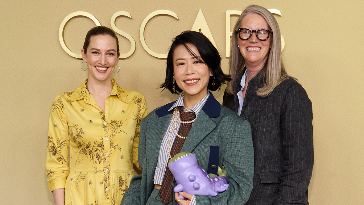 Elio directors Madeline Sharafian and Domee Shi, along with producer Mary Alice Drumm, pose for a photo against a yellow backdrop during the Oscars nominees luncheon.