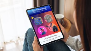 Person holding a tablet displaying the D23 Fanfare newsletter, featuring colorful graphics of exclusive D23 merchandise and the headline &lsquo;New D23 Premium Items,&rsquo; viewed in a cozy indoor setting.