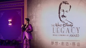 Disney Legend Lea Salonga performs onstage during the recent Legacy Award ceremony at Hong Kong Disneyland Resort. The graphic for the Legacy Award, featuring a sketch of Walt Disney, is seen behind her.