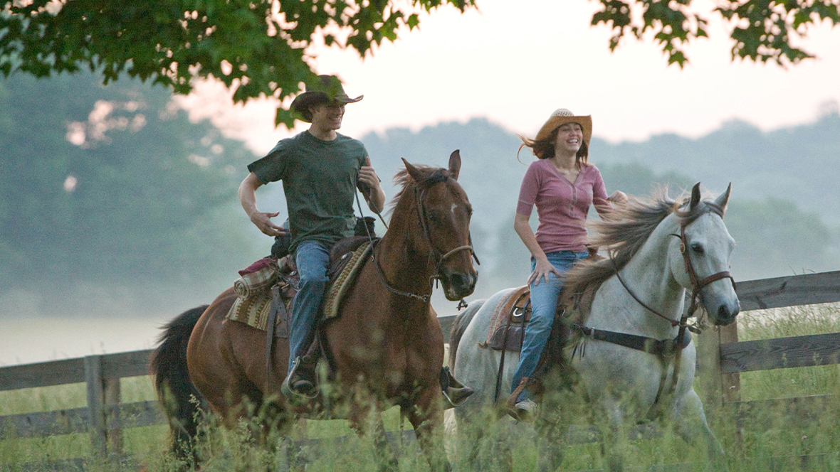 An image from Hannah Montana: The Movie, starring Disney Legend Miley Cyrus. Cyrus is seen riding on horseback with costar Lucas Till as Travis.