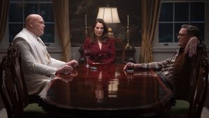 An image from Daredevil: Born Again, season 2, featuring Vincent D&rsquo;Onofrio as Fisk (left), Aylet Zurer as Vanessa Fisk (middle), and Matthew Lillard as Mr. Charles (right), sitting around a dining table.