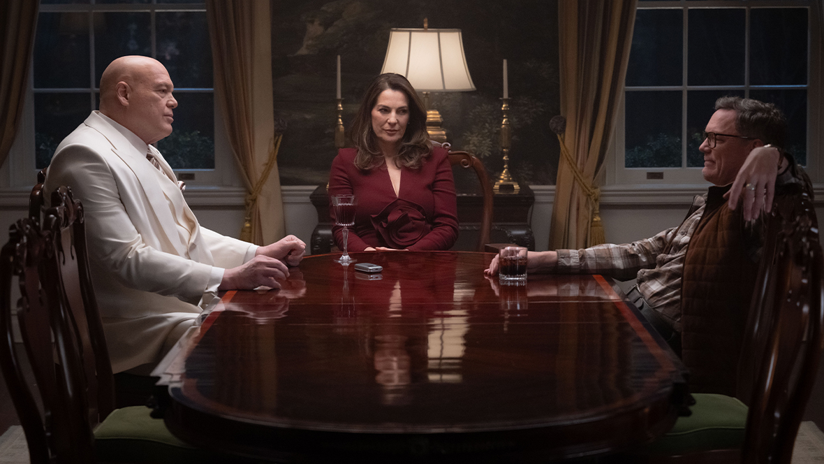 An image from Daredevil: Born Again, season 2, featuring Vincent D&rsquo;Onofrio as Fisk (left), Aylet Zurer as Vanessa Fisk (middle), and Matthew Lillard as Mr. Charles (right), sitting around a dining table.