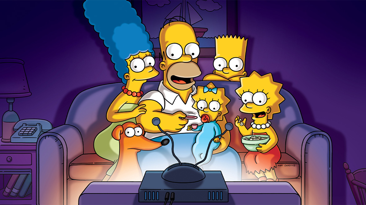 An image of The Simpsons&mdash;from left to right, Marge, Homer, Maggie, Bart, and Lisa; their dog Santa&rsquo;s Little Helper is sitting at Marge and Homer&rsquo;s feet. The family is crowded onto their couch and watching TV, and the light from the set is illuminating their faces.