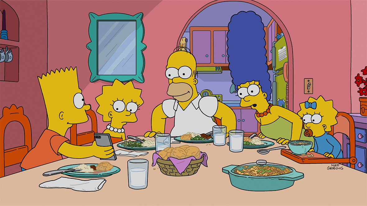 An image from the 800th episode of The Simpsons; from left to right, Bart, Lisa, Homer, Marge, and baby Maggie are sitting around the kitchen table, and Bart is showing them something on his phone.