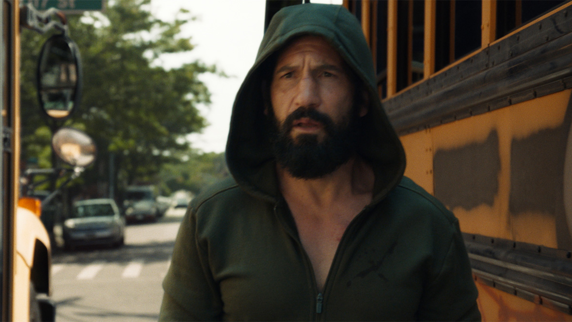 Frank Castle/The Punisher, played by Jon Bernthal, stands next to a school bus in scene from A Marvel Television Special Presentation: The Punisher: One Last Kill on Disney+.