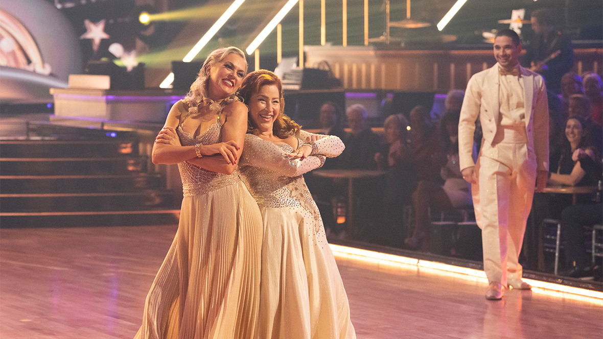 An image from the &ldquo;Dedication Night&rdquo; episode of Dancing with the Stars, Season 34; contestant Elaine Hendrix, right, and Lisa Ann Walter, left, are smiling and standing back-to-back on the dance floor, while Hendrix&rsquo;s partner Alan Bersten watches from the right-hand side of the floor. All three are wearing cream-colored fancy ballroom-style outfits.