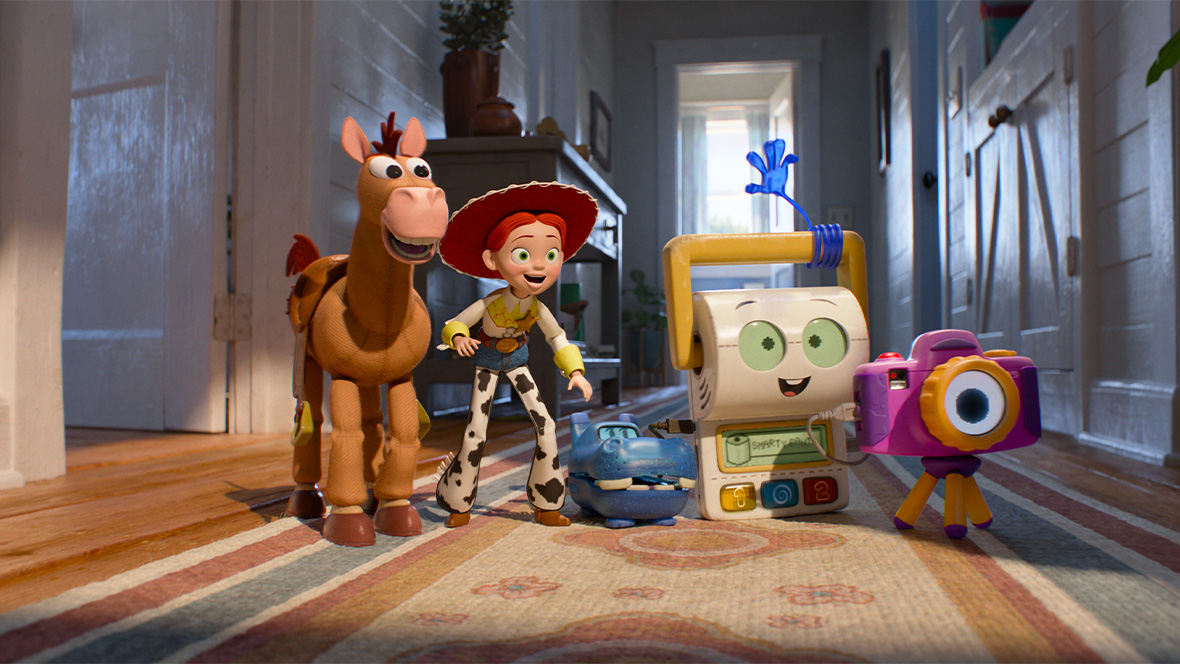 In an image from Disney and Pixar&rsquo;s Toy Story 5, from left to right, Bullseye, Jessie (voiced by Joan Cusack), Atlas (voiced by Craig Robinson), Smarty Pants (voiced by Conan O&rsquo;Brien), and Snappy (voiced by Shelby Rabara) are standing in a hallway and smiling at something off camera to the right.
