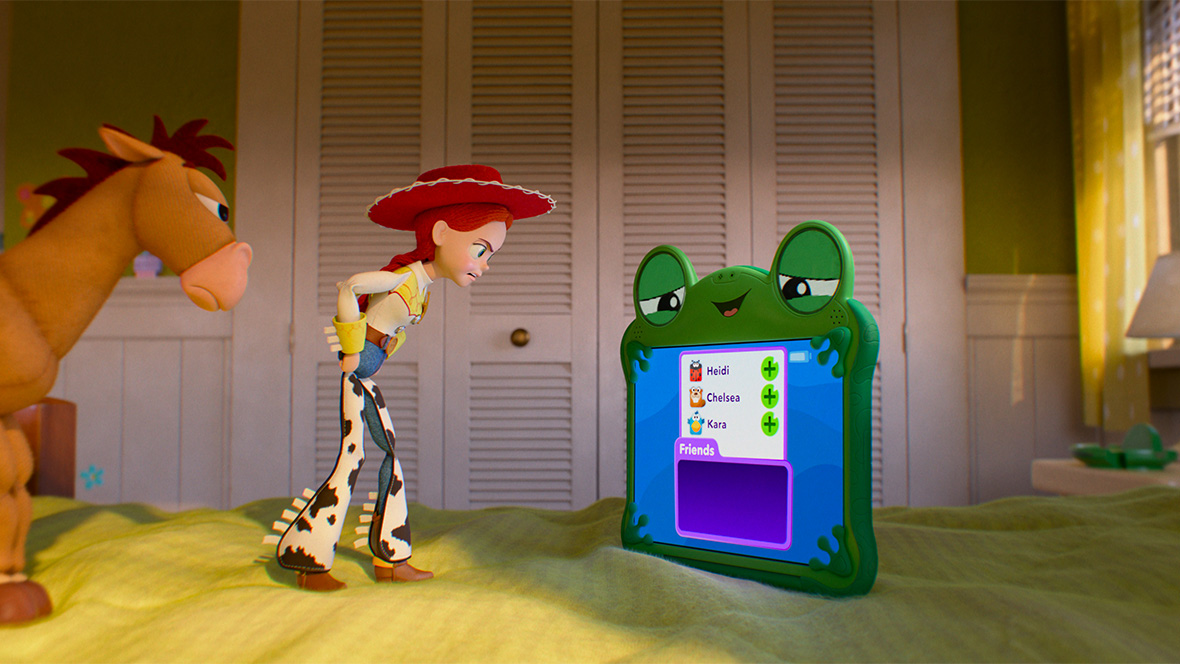 In an image from Disney and Pixar&rsquo;s Toy Story 5, Bullseye, left, and Jessie (voiced by Joan Cusack), middle, are looking at something on Lilypad&rsquo;s (voiced by Greta Lee) screen, at right. All three are on top of a bed with a green bedspread.