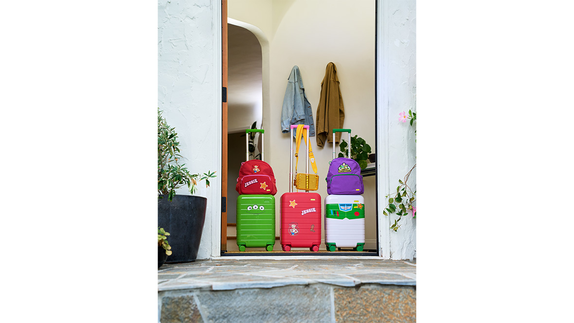 Three pieces of luggage inspired by Toy Story 5 from Away, seen in a doorway.