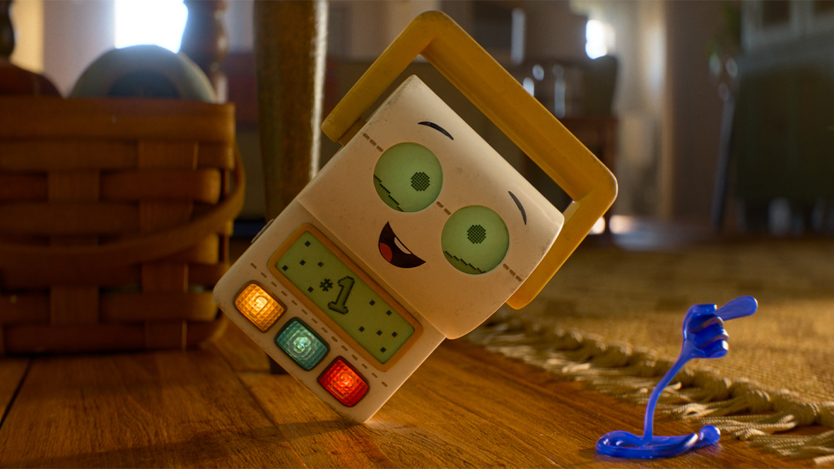 In an image from Disney and Pixar&rsquo;s Toy Story 5, Smarty Pants (voiced by Conan O&rsquo;Brien) is on the floor, leaning onto one corner of his body, and smiling. A blue figure in the shape of a hand is in front of him, pointing to the right.