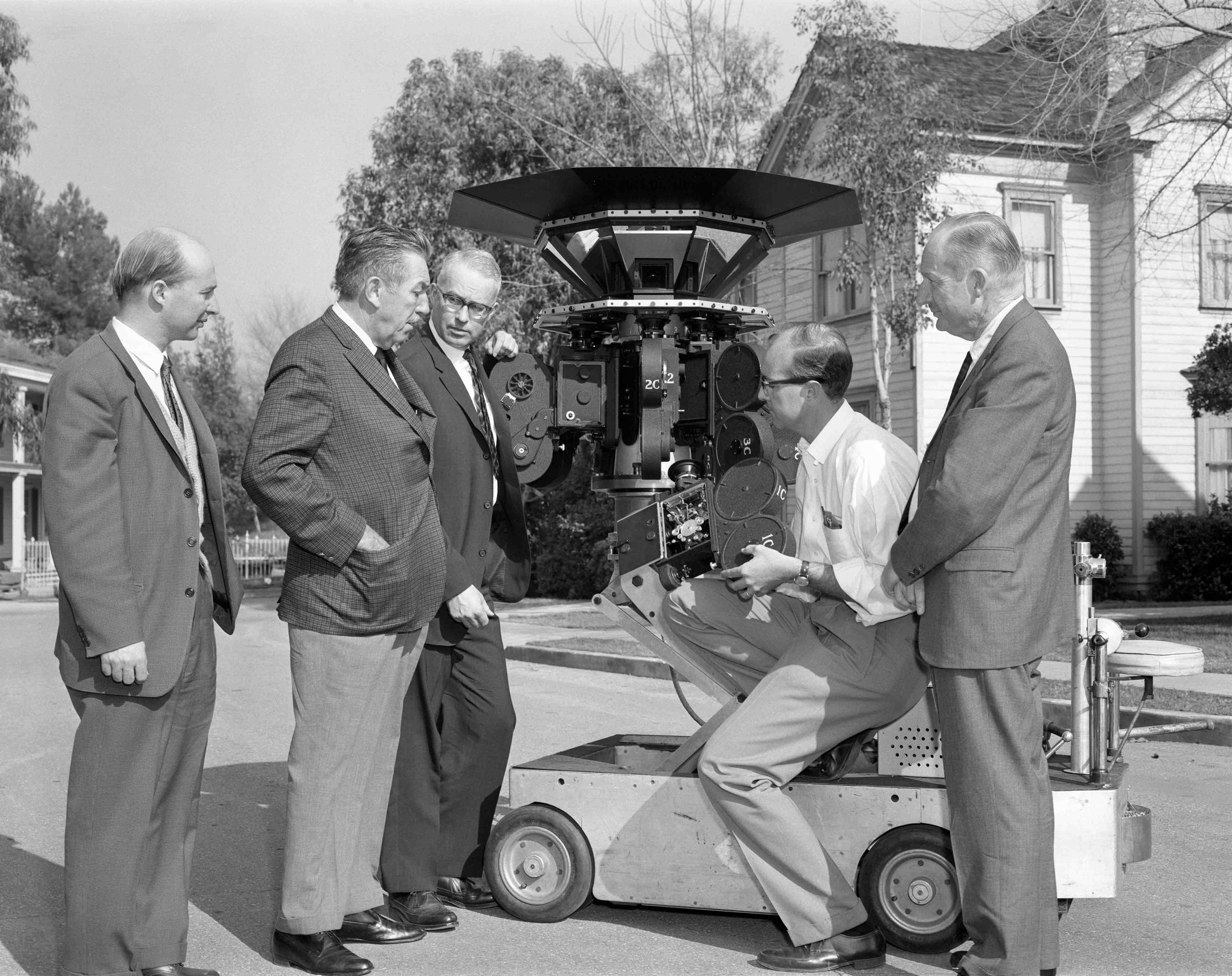 Walt Disney with Don Iwerks and others, looking at a piece of camera equipment.