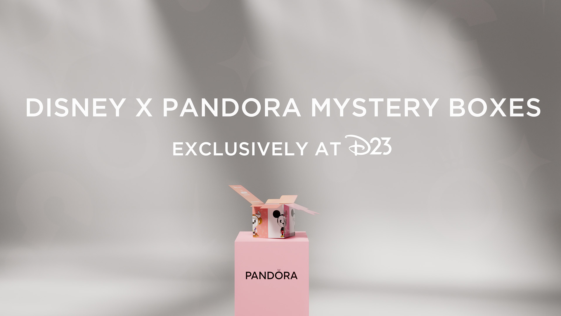 A branded display promotes Disney x Pandora Mystery Boxes exclusively at D23, featuring an open Disney-themed mystery box atop a pink Pandora pedestal against a soft gray background with large white text.