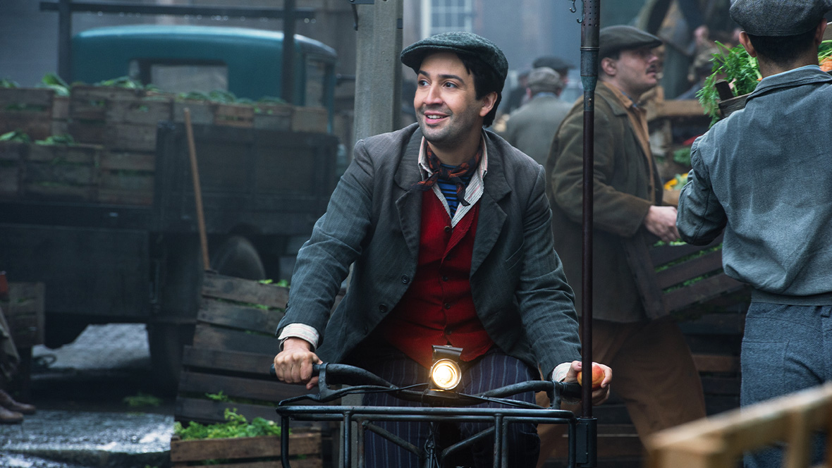 Bert, played by Disney Legend Lin-Manuel Miranda, rides a bike through London in a scene from Disney's Mary Poppins Returns.