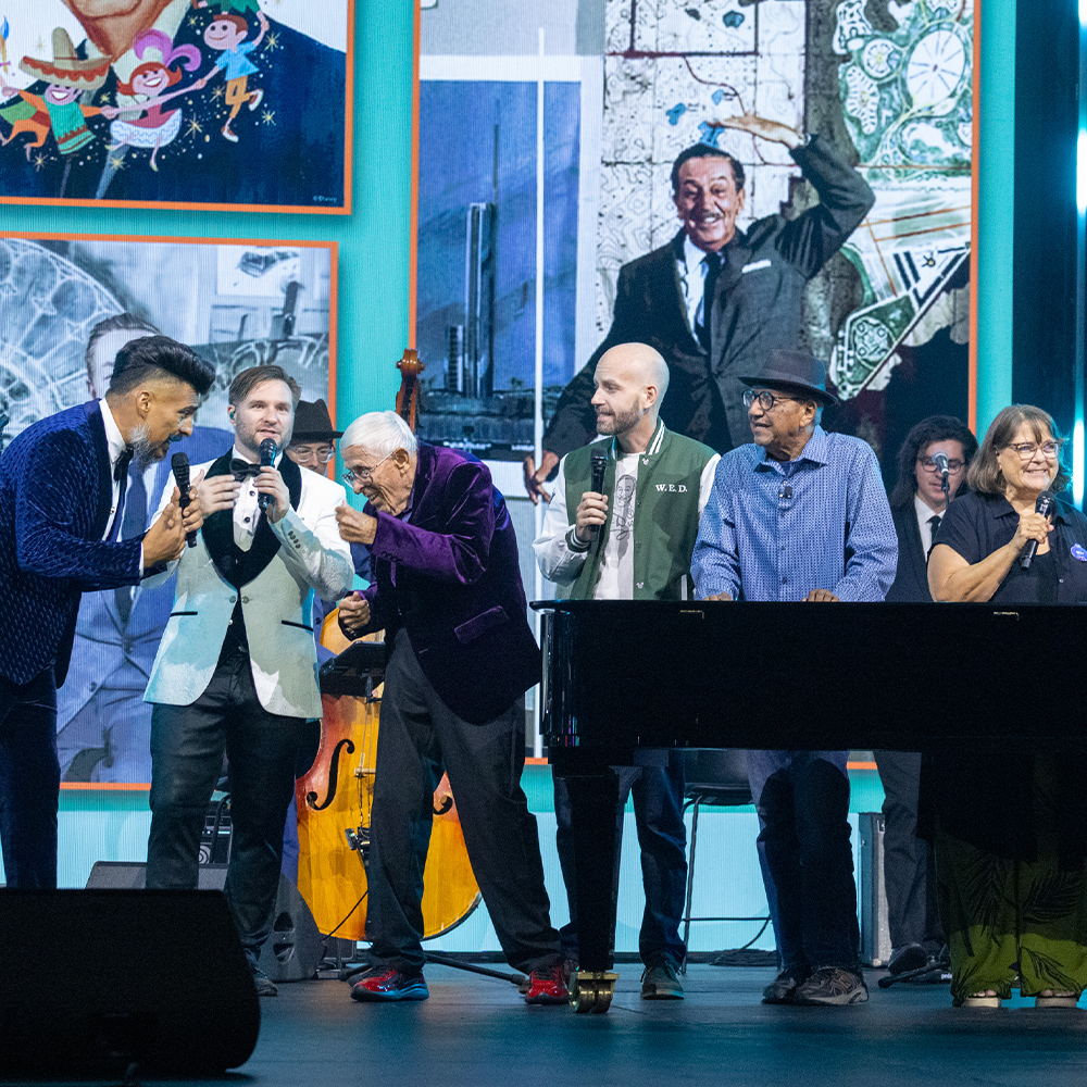 Panelists and performers gather onstage during the Walt Disney: 125 Years of Inspiration presentation at D23: The Ultimate Disney Fan Event.