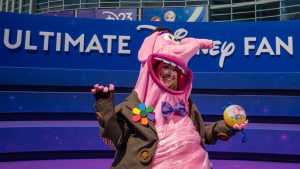 A D23 attendee cosplaying as Bing Bong from Disney and Pixar&rsquo;s Inside Out poses in front of D23: The Ultimate Disney Fan Event signage.