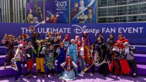 D23 attendees wearing Kingdom Hearts cosplay costumes pose together in front of D23: The Ultimate Disney Fan Event signage