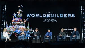 Panelists participate in a Disney Worldbuilders discussion onstage during D23: The Ultimate Disney Fan Event 2026, beneath a large screen displaying the documentary title and artwork.