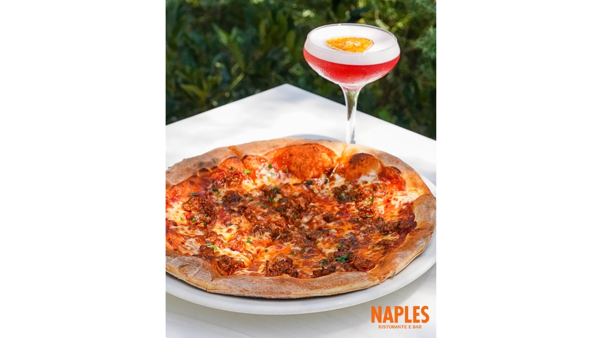Pizza and a red cocktail are displayed on an outdoor table during the Hulu Animayhem dining promotion at Naples Ristorante e Bar.