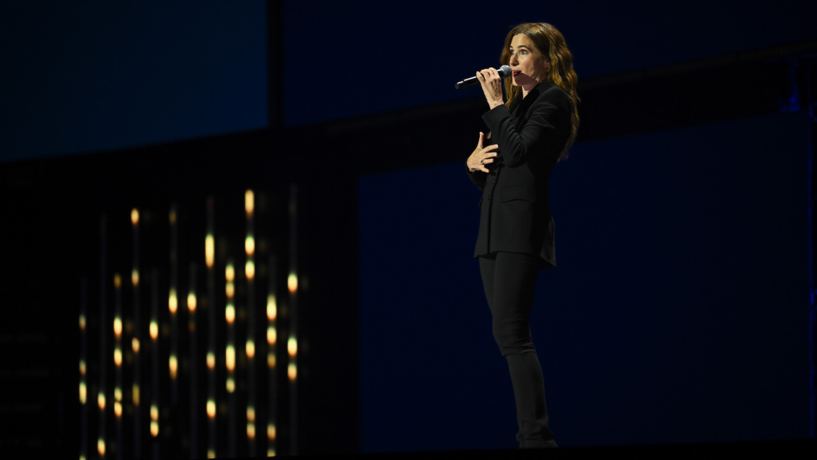 An image of Kathryn Hahn, on stage at the Honda Center during the Disney Entertainment Showcase at D23: The Ultimate Disney Fan Event, telling the crowd about the upcoming live-action Tangled.