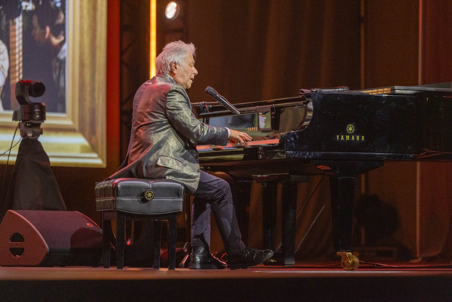 Alan Menken performs at a grand piano during a presentation at D23: The Ultimate Disney Fan Event.