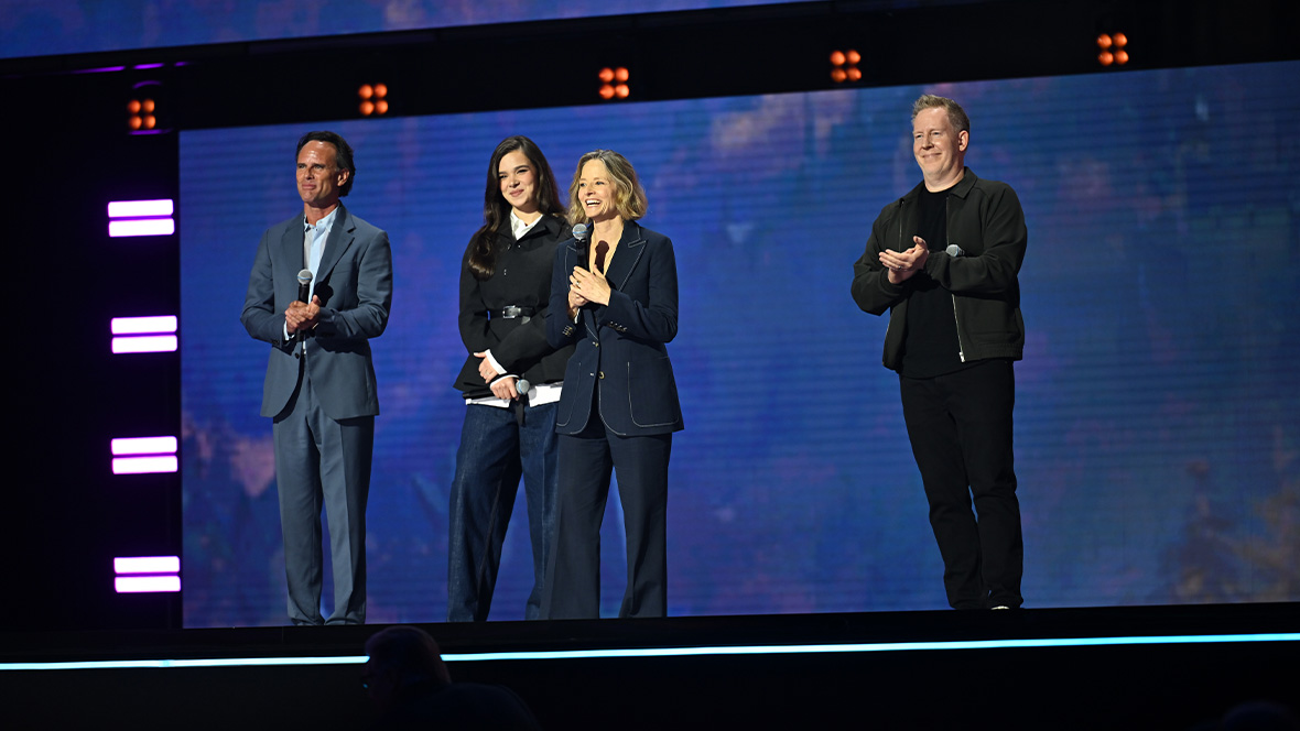 An image of Walton Goggins, Hailee Steinfeld, Jodie Foster, and Jared Bush on stage at the Honda Center during the Disney Entertainment Showcase at D23: The Ultimate Disney Fan Event talking about the upcoming Disney animated film Hexed.