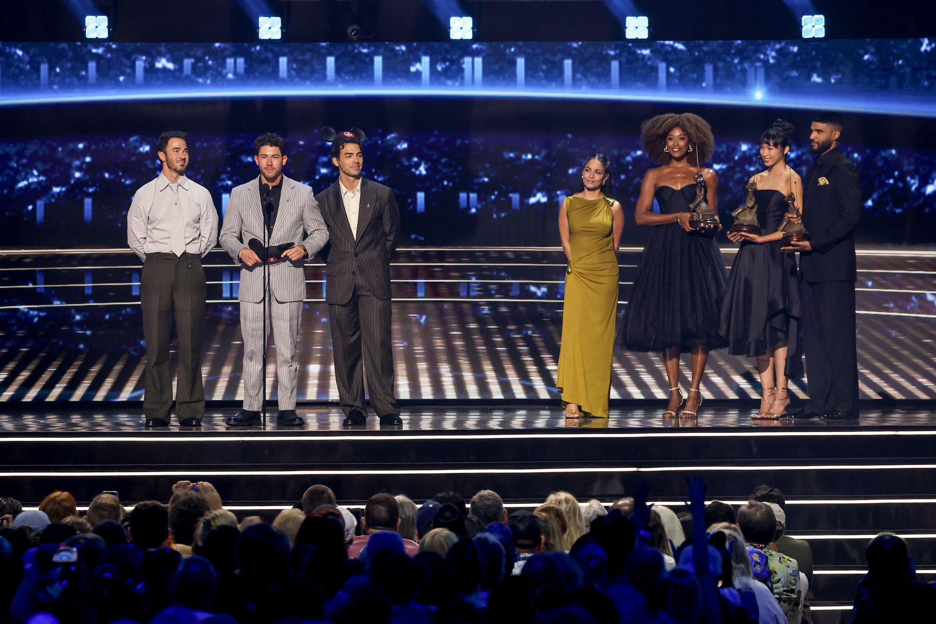 Members of the Jonas Brothers and Disney Legends honorees stand onstage during the 2026 Disney Legends Awards ceremony.