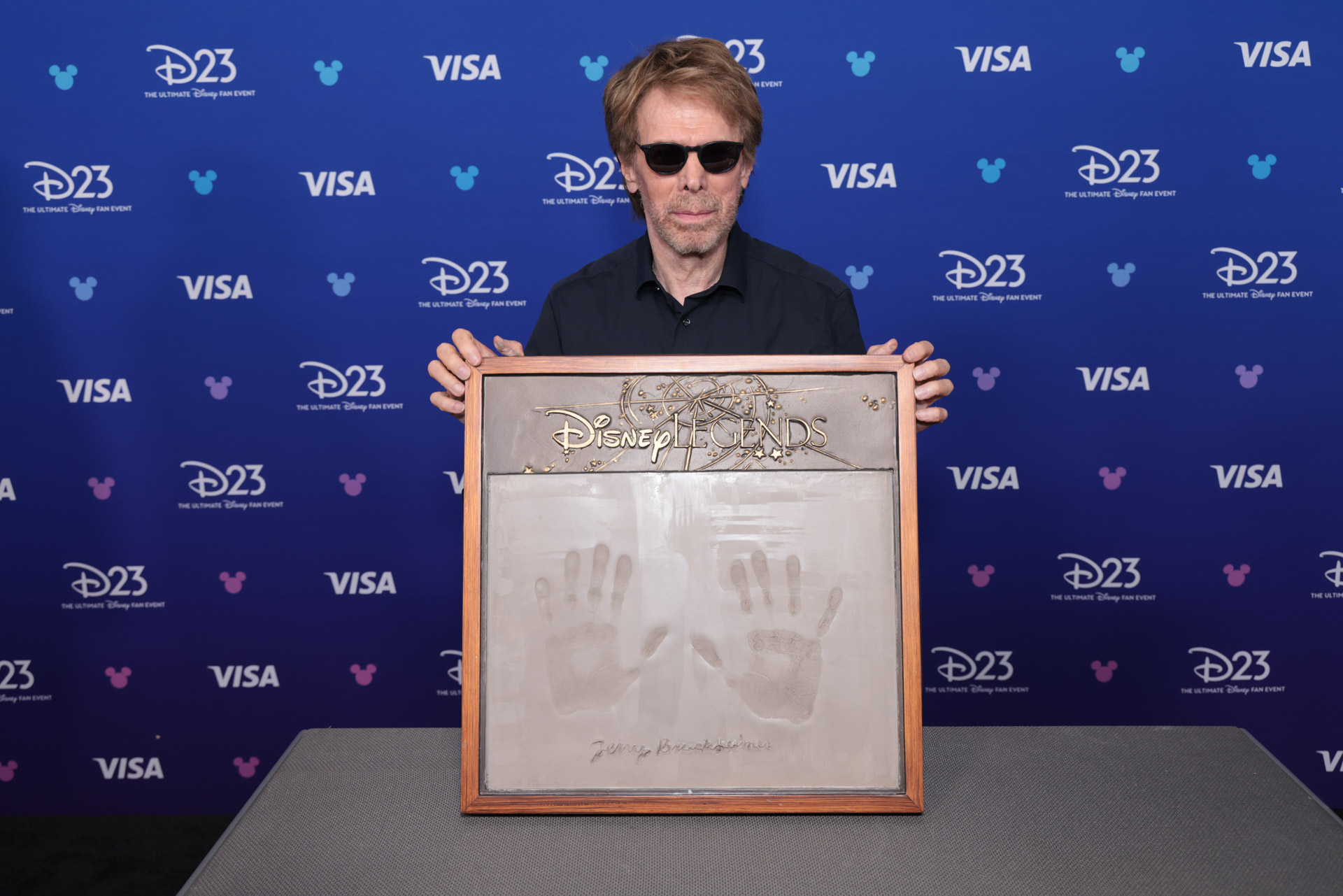 Jerry Bruckheimer poses with his Disney Legends handprint plaque at D23: The Ultimate Disney Fan Event.