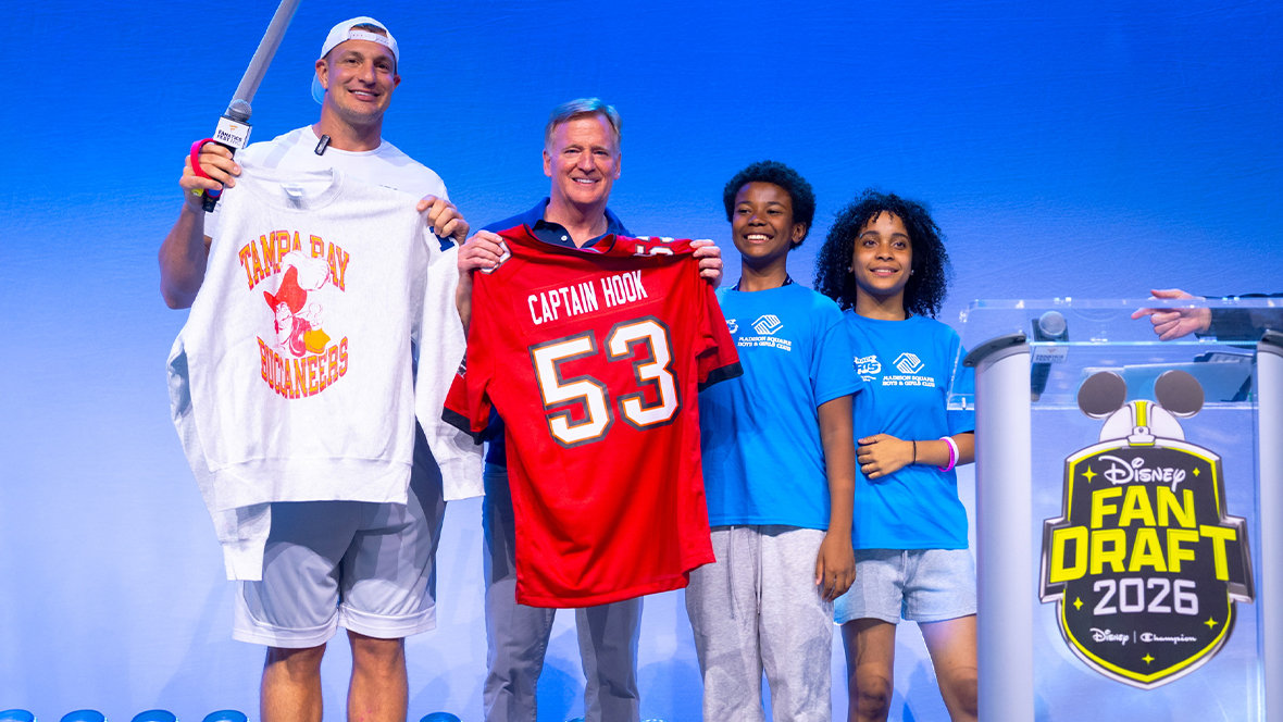 Participants including Rob Gronkowski and NFL Commissioner Roger Goodell hold Disney-inspired football apparel and a Captain Hook jersey onstage during the Disney Fan Draft 2026 event.