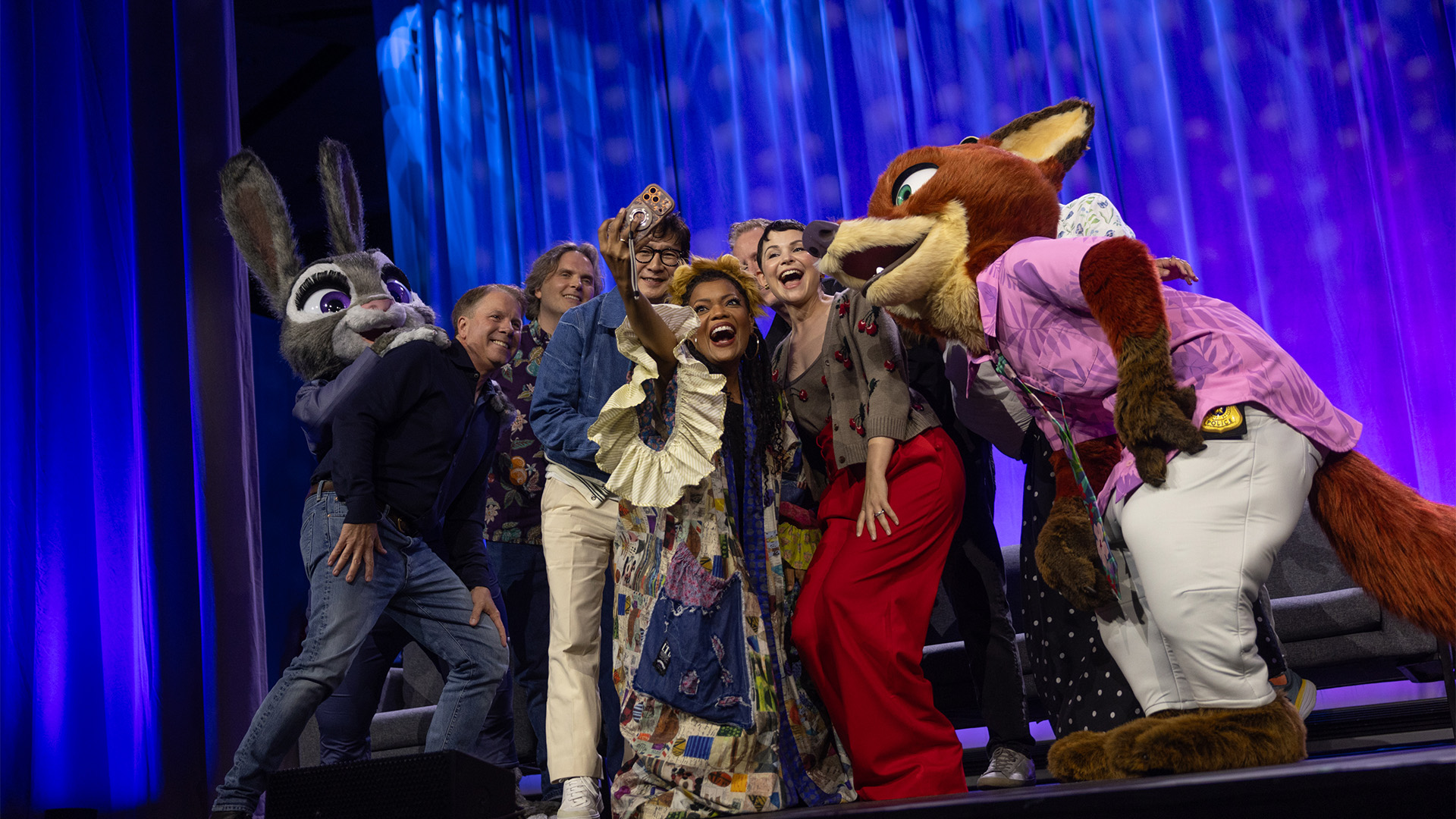 Judy Hopps, Clark Spencer, Byron Howard, Ke Huy Quan, Yvette Nicole Brown, Jared Bush, Ginnifer Goodwin, Michael Giacchino, Yvett Merino, and Nick Wilde snap a selfie onstage during the &lsquo;Zootopia: Ten Years in the Mammal Metropolis&rsquo; presentation during D23: The Ultimate Disney Fan Event.