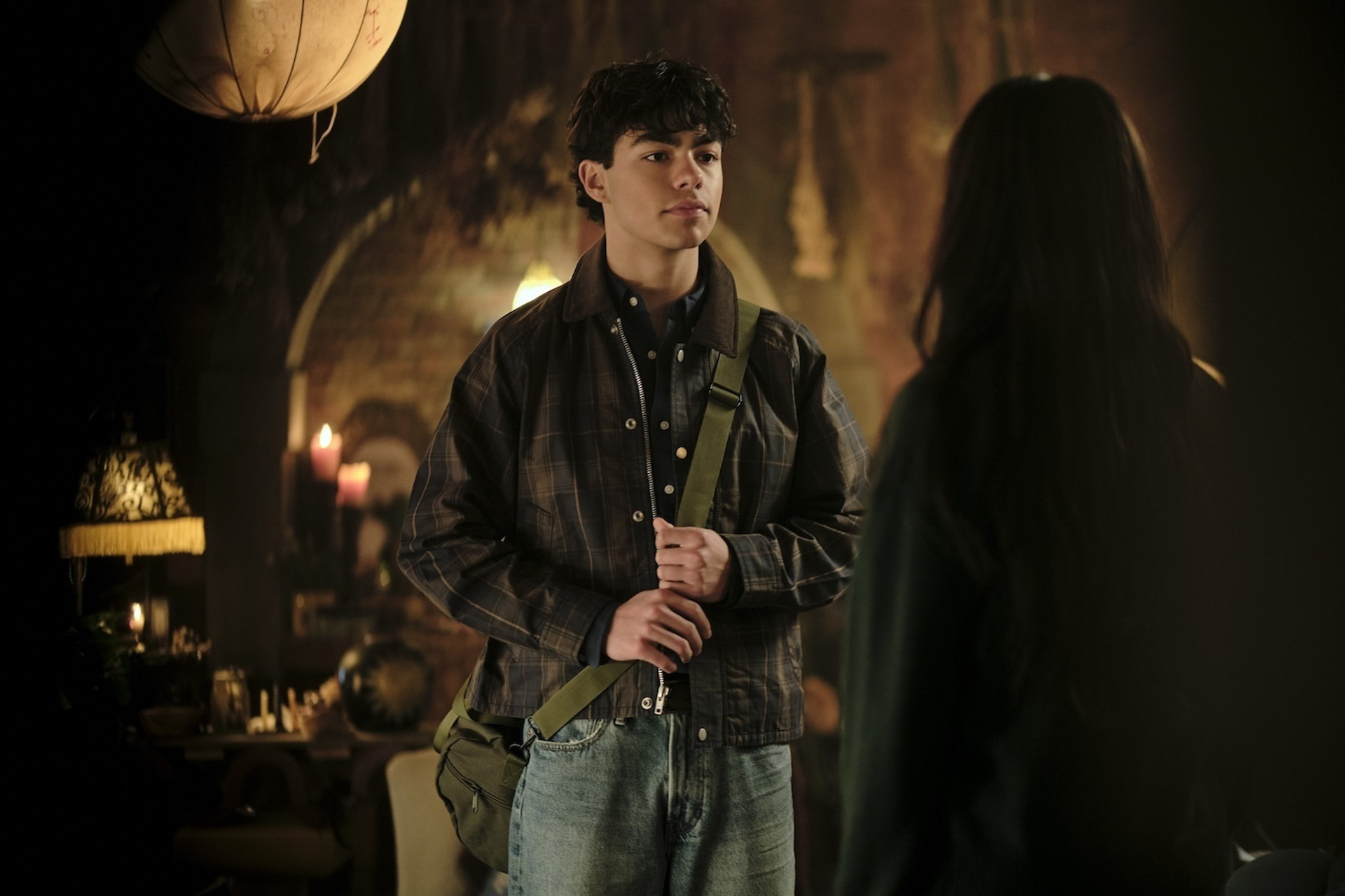 Jake, played by Malachi Barton, holds onto his messenger bag strap and speaks with Briar, played by Malina Weissman, in a scene from Disney&rsquo;s Coven Academy.