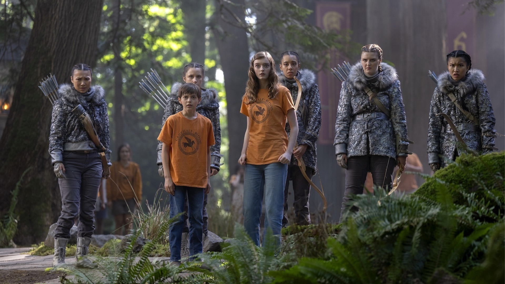 Nico di Angelo (Levi Chrisopulos), Bianca di Angelo (Olive Abercrombie), and the Hunters of Artemis gather in the woods in Season 3 of Percy Jackson and the Olympians.