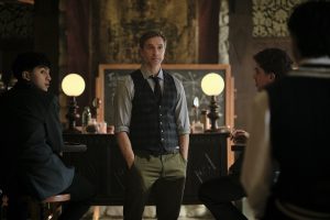 Mr. Cole, played by Devon Sawa, stands in the center of a classroom. Two students have their backs turned to him as they face someone out of frame in a scene from Coven Academy.