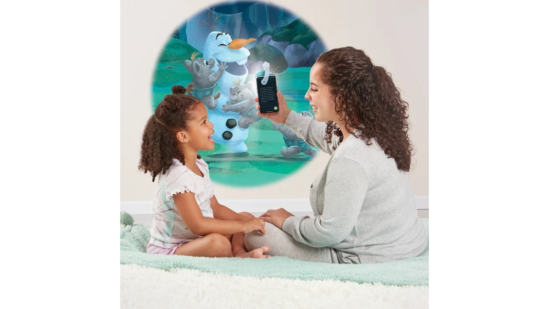 Adult and child using a smartphone to project an interactive Olaf story scene from Disney Frozen onto a wall.