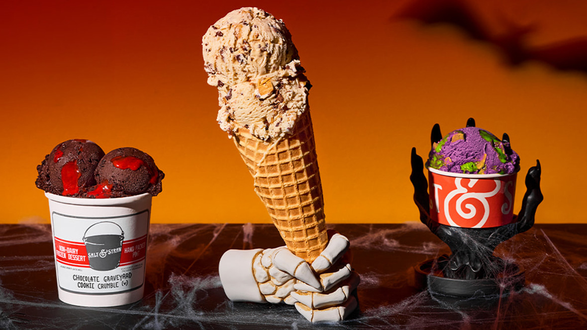 Three Halloween-themed Salt & Straw ice cream treats, including a cone and two specialty scoops, are displayed with seasonal decorations.