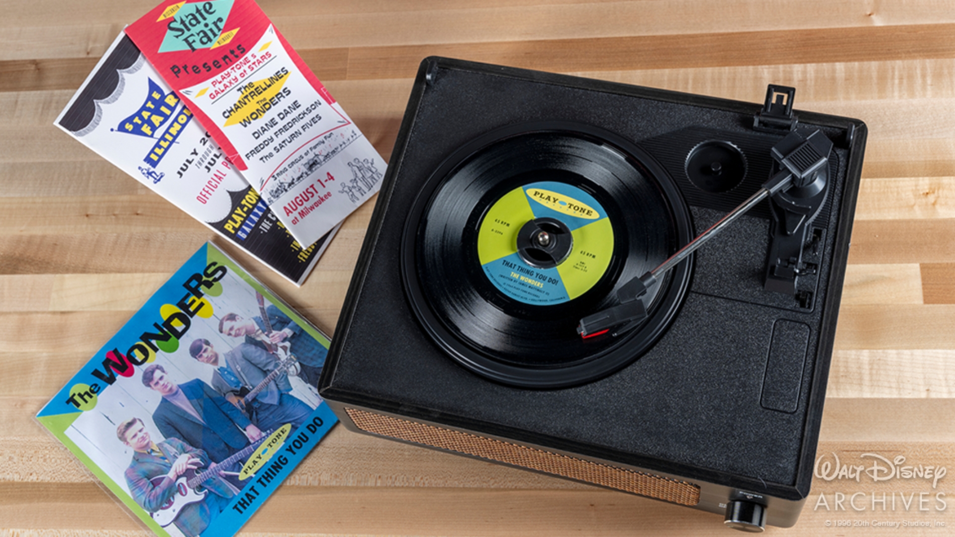 Props from That Thing You Do! arranged for display, including a vinyl record of the title song, &ldquo;That Thing You Do!,&rdquo; beside a mock album sleeve featuring artwork for the Wonders. Surrounding the record are colorful Play-Tone Galaxy of Stars Tour brochures and promotional materials advertising the fictional recording label and its artists, capturing the film&rsquo;s 1960s pop music aesthetic.